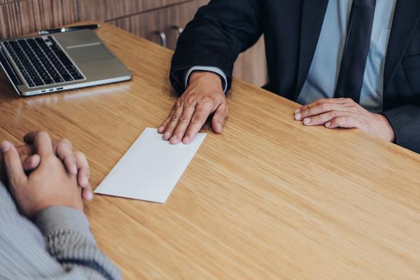 Man sliding an envelope across a table to another man