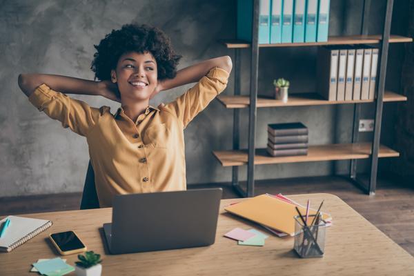 Woman leaning back at her desk with her hands behind her head